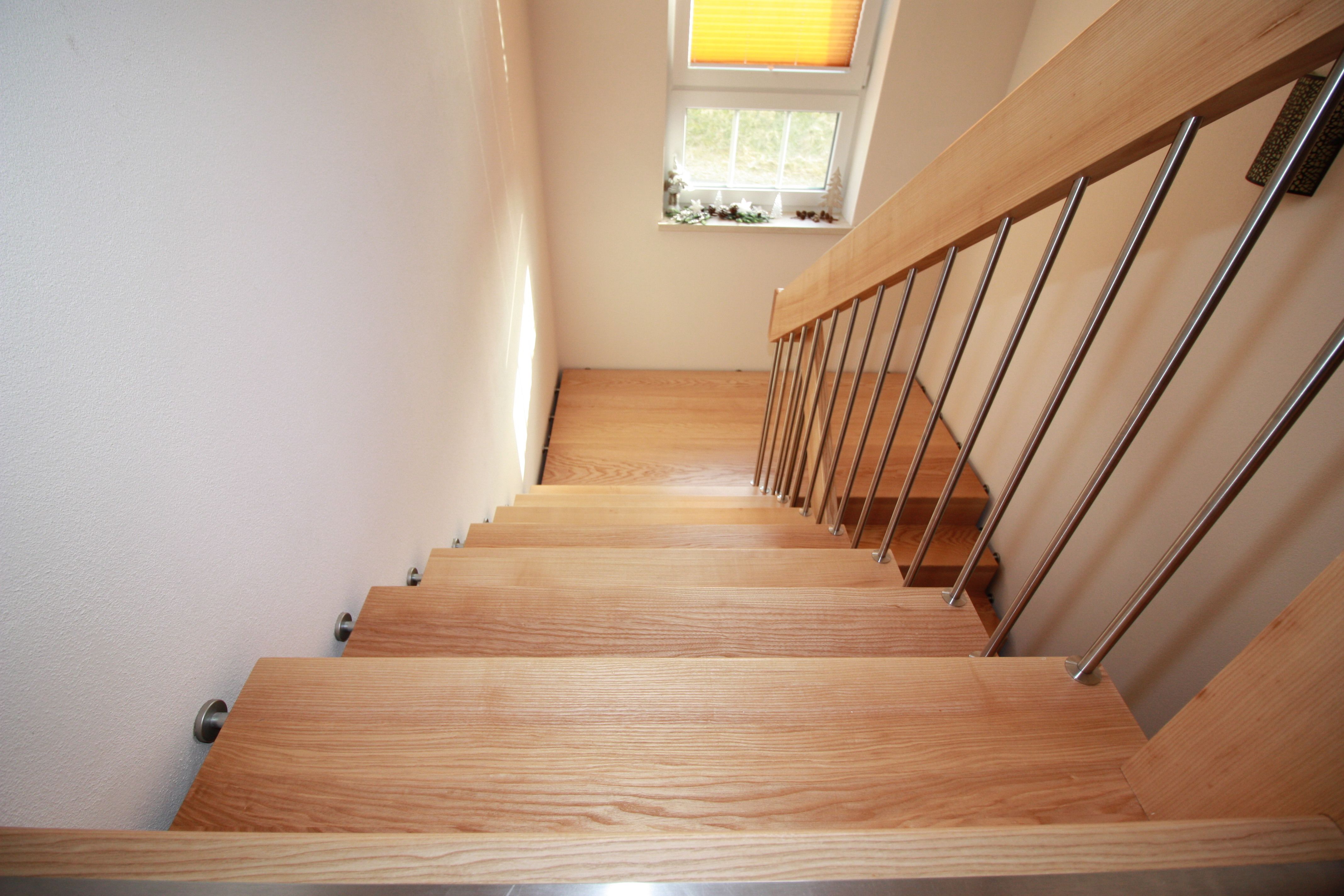 Gerade Treppe mit hellen Holzstufen, Edelstahlstäben und Holzhandlauf, Blick hinab zum Podest unter dem Fenster