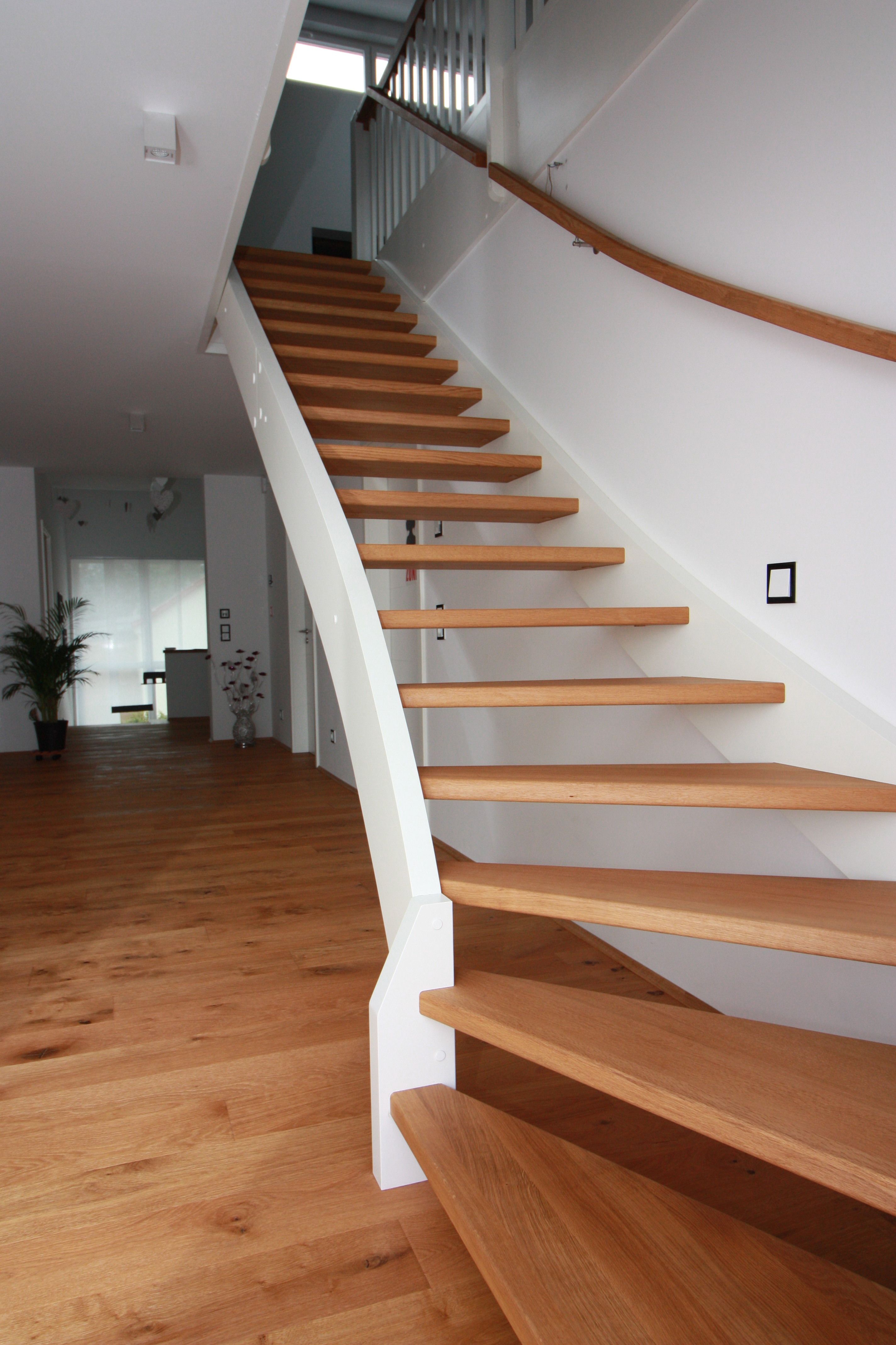 Gewendelte Treppe mit offenen hellen Holzstufen, weißer geschwungener Wange und Wandhandlauf aus Holz