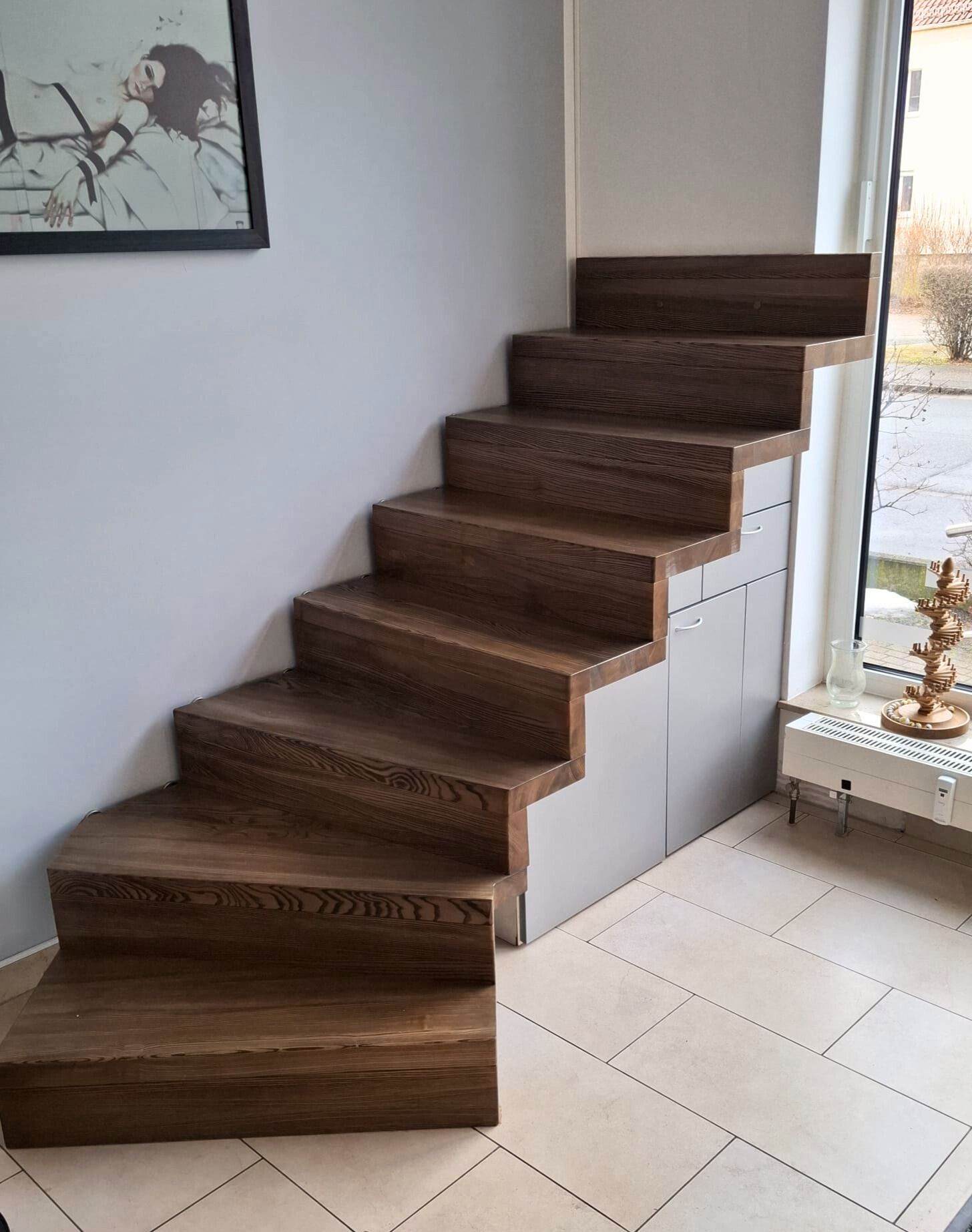 Treppe in Faltwerk-Optik aus dunklem Holz mit Einbauschrank unter den Stufen, ausgestellt in Dresden
