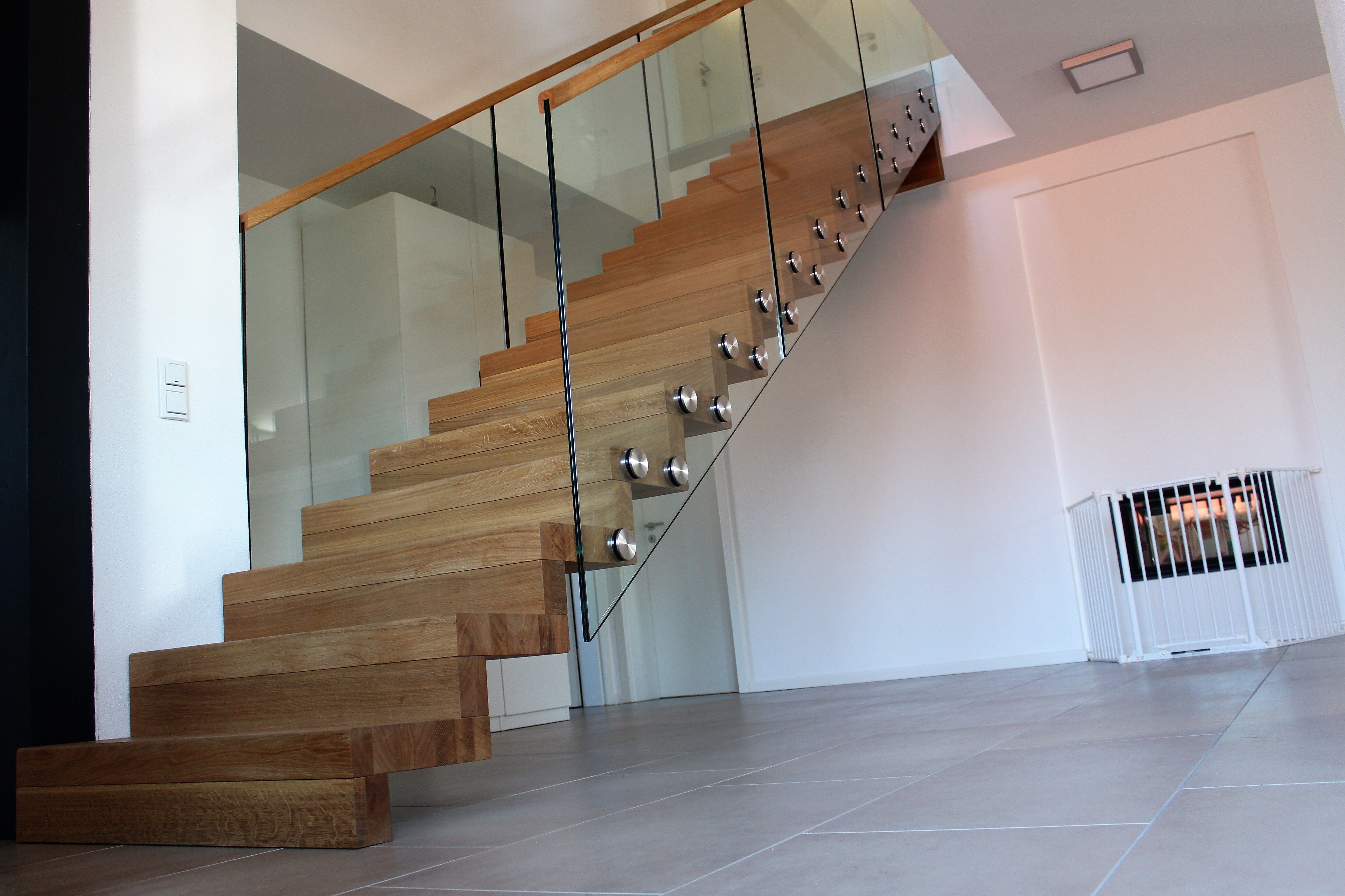 Gerade Treppe aus massiven hellen Holzblockstufen mit Glasgeländer an Punkthaltern und Holzhandlauf im Wohnbereich