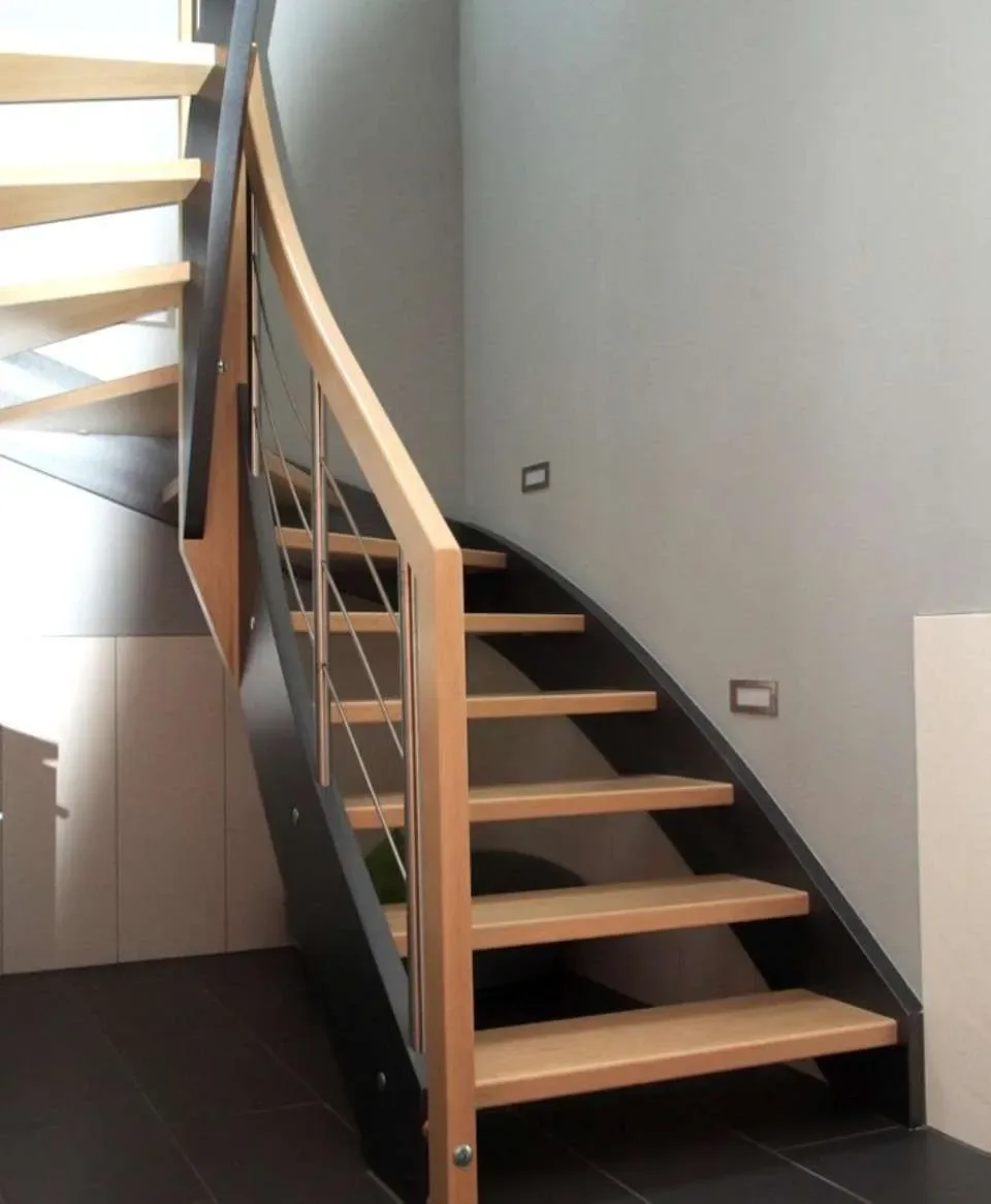 Gewendelte Treppe mit anthrazitfarbenen Wangen, offenen hellen Holzstufen und Holzhandlauf mit Edelstahlstäben